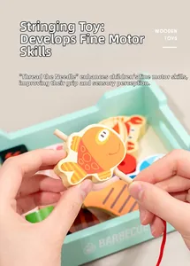 Close-up of lacing marine-themed wooden blocks with a red string for kids