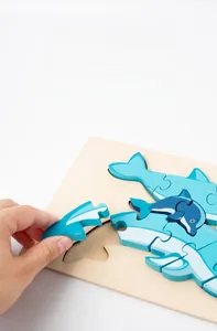Close-up of placing a blue wooden dolphin puzzle piece into the natural base board