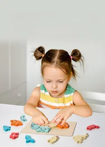 Little girl playing with wooden animal puzzles for early education and cognitive learning