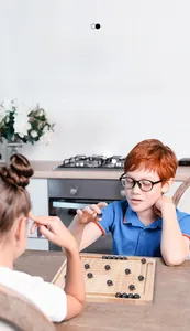 Children playing the magnetic battle chess game on a wooden board at a kitchen table