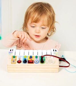 Detail of wooden busy board with LED light switches and piano keys for toddler early learning
