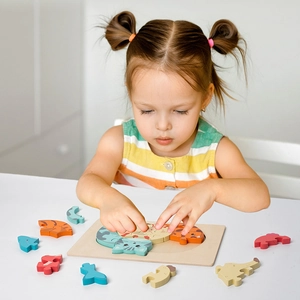 Toddler playing with colorful wooden animal puzzle blocks on a natural wood base