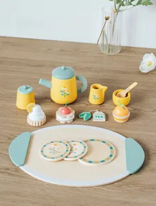 Dettaglio di set da tè in legno con teiera floreale, cupcake e bustina su un vassoio