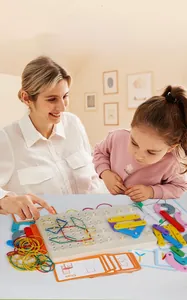 Child interacts with wooden geoboard toy, rubber bands, and cards for STEM learning