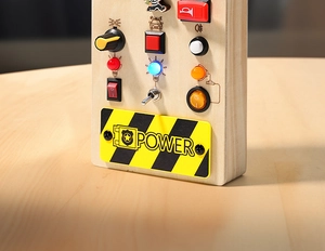 Detailed close-up of wooden busy board featuring colorful LED lights and toggle switches