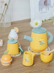 Dettaglio di un set da tè in legno con teiera, tazze a margherita e dolci giocattolo