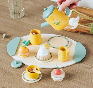 Dettaglio del set da tè in legno con teiera a margherite e dolci giocattolo in miniatura