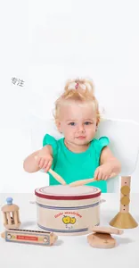 Detailed view of child playing with wooden musical toys including drum, harmonica and bell