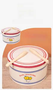 Macro view of a musical drum toy with little musician print and wooden drumsticks