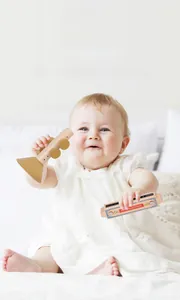 Toddler playing with wooden toy trumpet and harmonica for musical early education