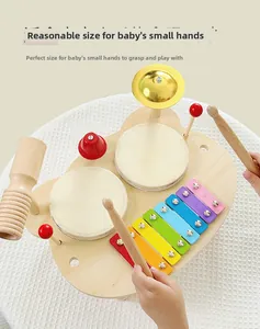 Toddler hand holding wooden mallet to play multi-functional musical xylophone and drum set