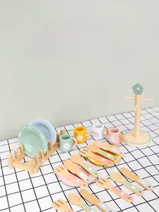 Detail of wooden play kitchen set with pastel cups and plates on checkered tablecloth
