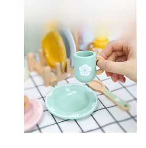 Detail of hand holding a mint green wooden toy cup with smooth edges for kids