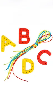 Detail of colorful alphabet threading blocks with multicolor rope for motor skills training