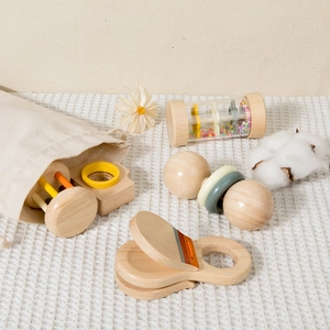 Natural wooden baby rattle set with storage bag on white waffle texture fabric