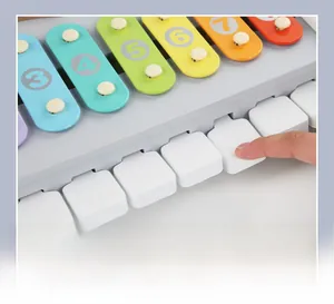 Gros plan d'une main pressant les touches d'un piano et d'un xylophone 2-en-1 en bois