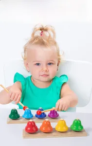 Close-up of colorful 8-note metal hand bells with wooden base and two mallets for children