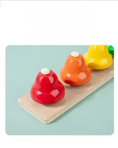 Detail of four colored bells on a wooden base for toddler musical education