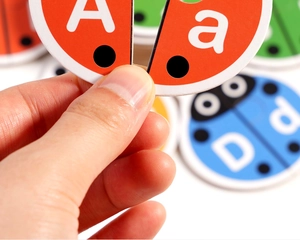 Close-up of child holding ladybug-shaped alphabet puzzle cards for letter matching