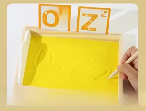 Gros plan sur un plateau de sable Montessori en bois avec sable jaune et cartes alphabet