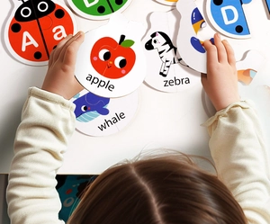 Top view of child matching colorful alphabet cards with animal patterns on a white table