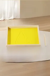 Détail du bac à sable Montessori en bois avec sable jaune et cartes alphabet pour l'écriture