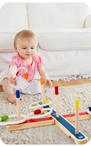Toddler playing with wooden ring toss game on beige rug to improve hand-eye coordination