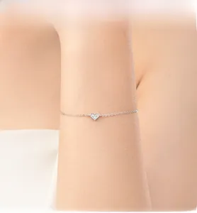 Dettaglio del bracciale a cuore in argento con tre zirconi luminosi su una catena sottile