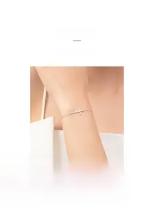 Close-up of a minimalist s925 sterling silver cross bracelet worn on a woman's wrist