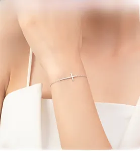 Close-up of minimalist S925 sterling silver horizontal cross bracelet on woman's wrist