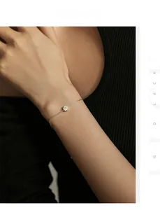 Detail of silver daisy chain bracelet worn on wrist with delicate white floral charm