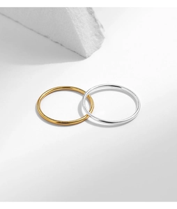 Minimalist polished silver and gold stacking rings on geometric white background
