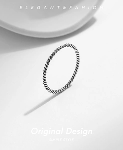 Macro detail of elegant S925 sterling silver rope twist ring on white ceramic base