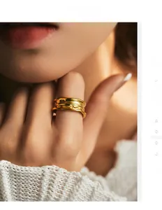 Detailed view of wide gold irregular textured ring on finger with white knit sweater