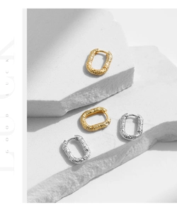 Close-up of textured S925 sterling silver rectangular hoop earrings in gold and silver