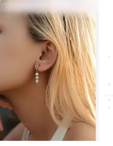 Detail view of S925 sterling silver drop earrings with three vertically set round diamonds