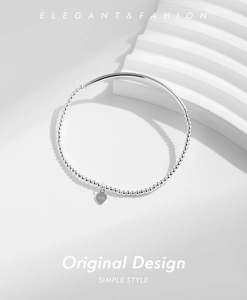 Dettaglio del bracciale in argento S925 con ciondolo a cuore su un piedistallo bianco
