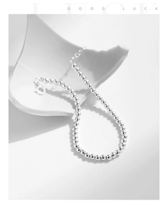 Détail d'un bracelet en perles argentées, finition brillante avec fermoir et extension