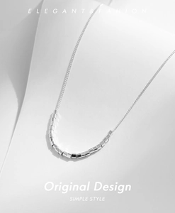 Close-up of minimalist s925 silver necklace featuring small geometric beads on a fine chain