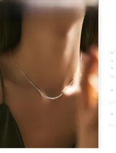 Detail of s925 silver minimalist necklace with geometric beads on a female model