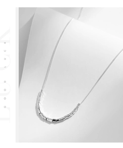 Macro detail of S925 sterling silver necklace with polished silver beads on a minimalist chain