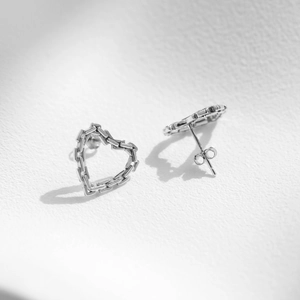 Minimalist S925 sterling silver hollow heart chain stud earrings on white textured background