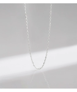 Detalle de cadena de plata s925 con reflejo de espejo sobre superficie gris minimalista