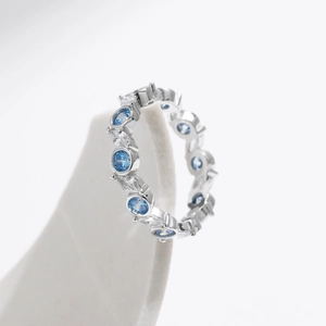 Bague éternité aux pierres bleues et claires sur un support géométrique blanc