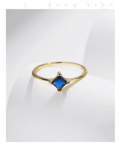 Detail of a square cut blue gemstone set in a gold S925 sterling silver minimalist ring