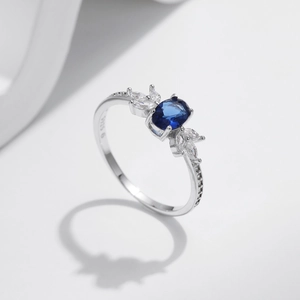S925 silver ring with oval blue sapphire and teardrop zircon accents on a white base