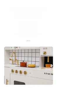 Detailed view of wooden play kitchen with golden faucet, knobs and orange cookware