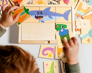 Gros plan détaillé de mains d'enfant assemblant des pièces de puzzle animalier en bois