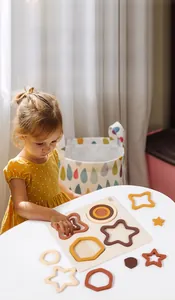 Close-up of a child playing with a wooden geometric shape matching puzzle on a table
