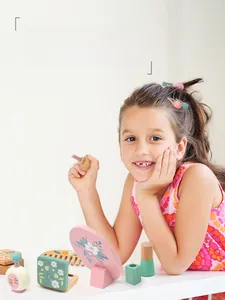 Girl playing with wooden makeup toy set including mirror lipstick and perfume